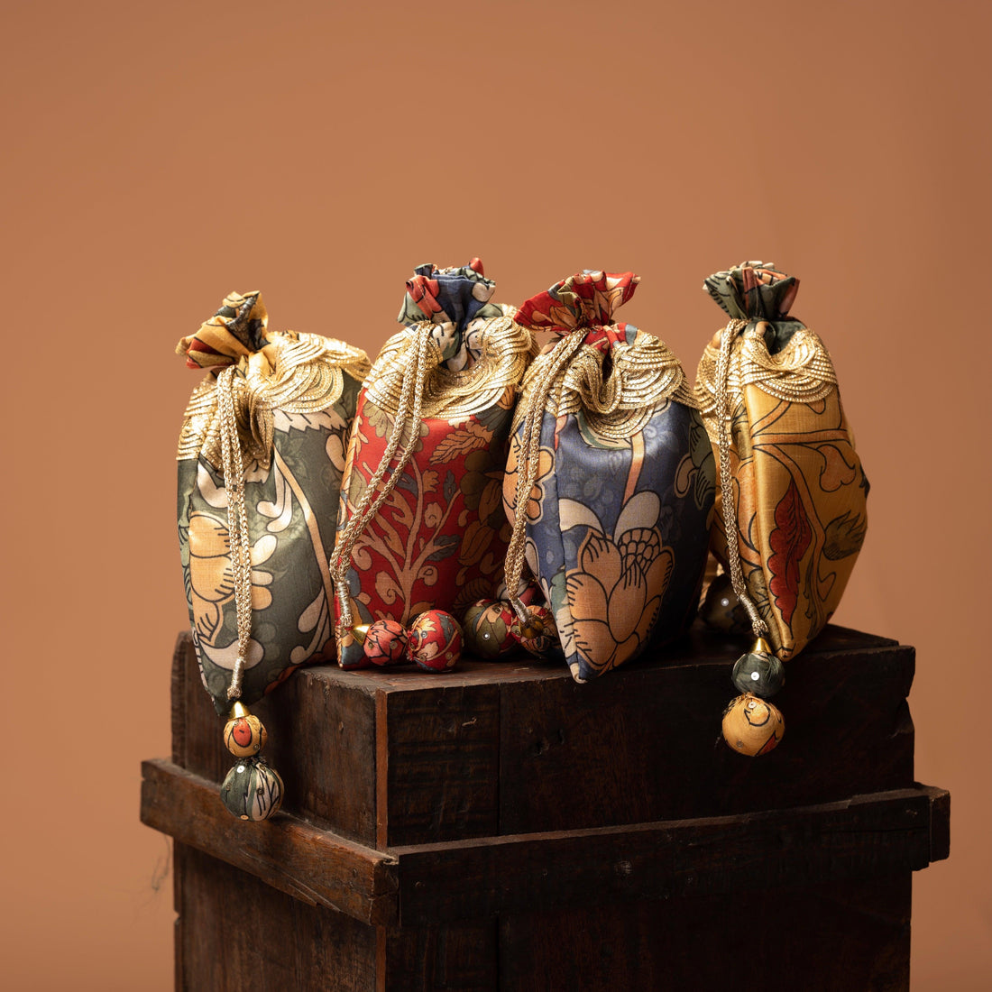 Set of four Kalamkari print mulberry silk potli bags with ball tassels — Ozel